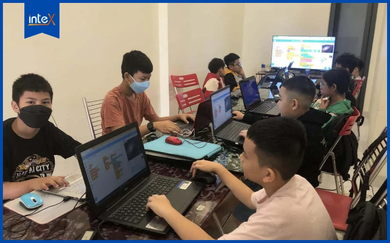 Học sinh tiểu học cùng nhau lập trình trên máy tính trong lớp học công nghệ