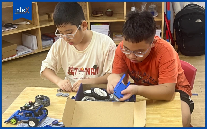 Hai học sinh lắp ráp robot giáo dục trong giờ học STEM, kết hợp học và chơi thông minh để phát triển tư duy sáng tạo.